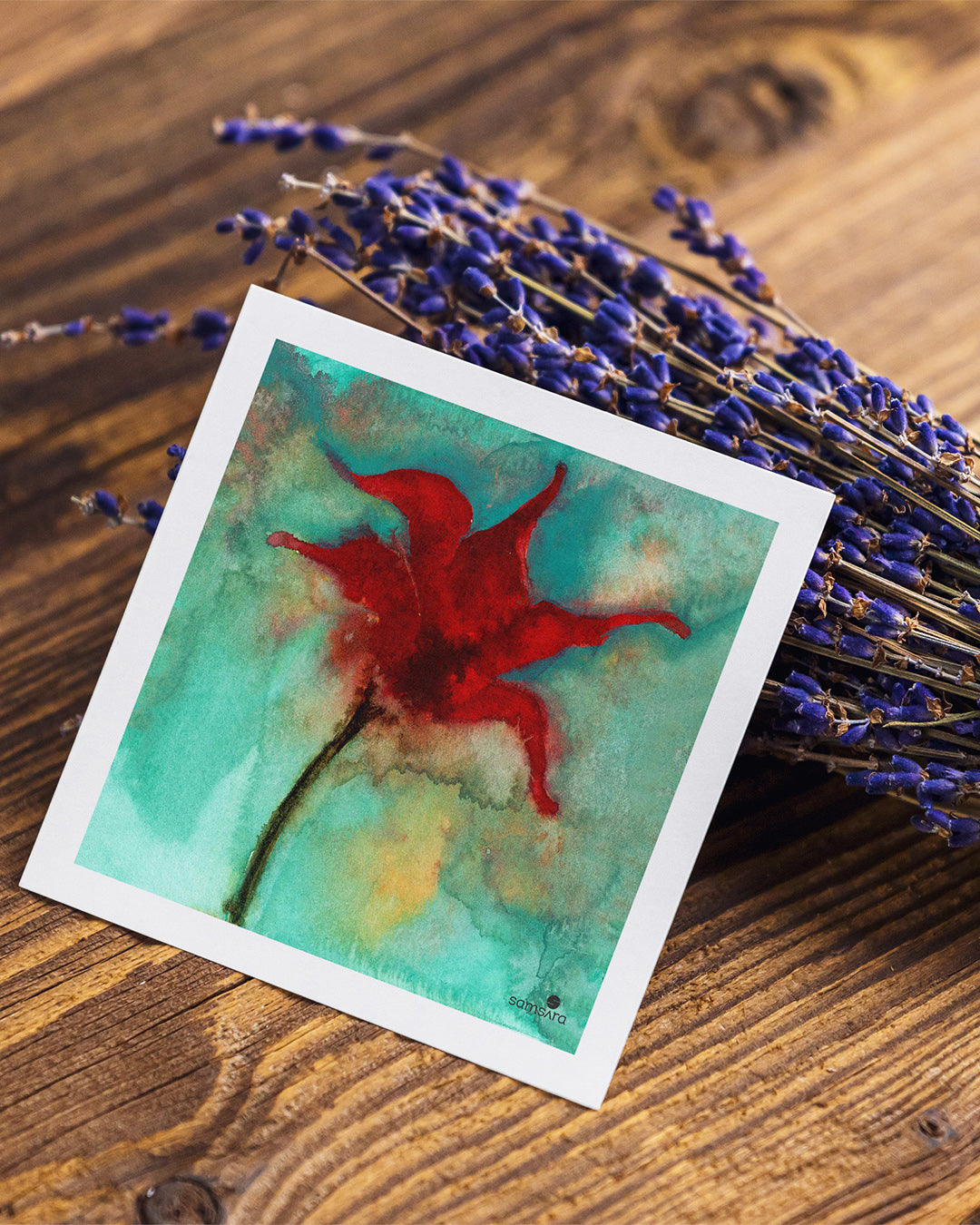 Watercolor painting of a red flower on a wooden surface with lavender.
