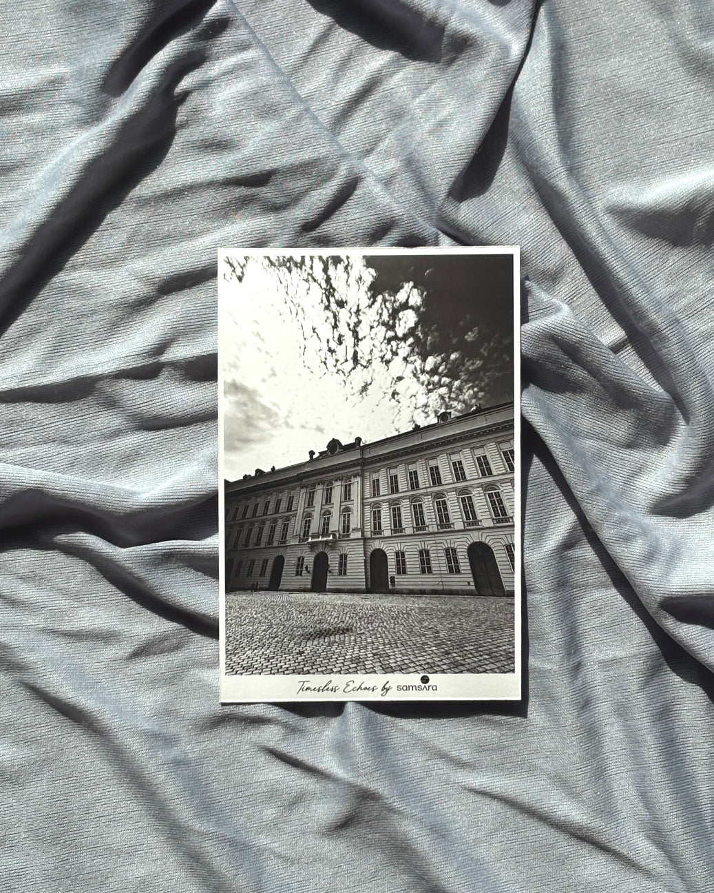 Black and white photo of a building on a textured gray fabric background
