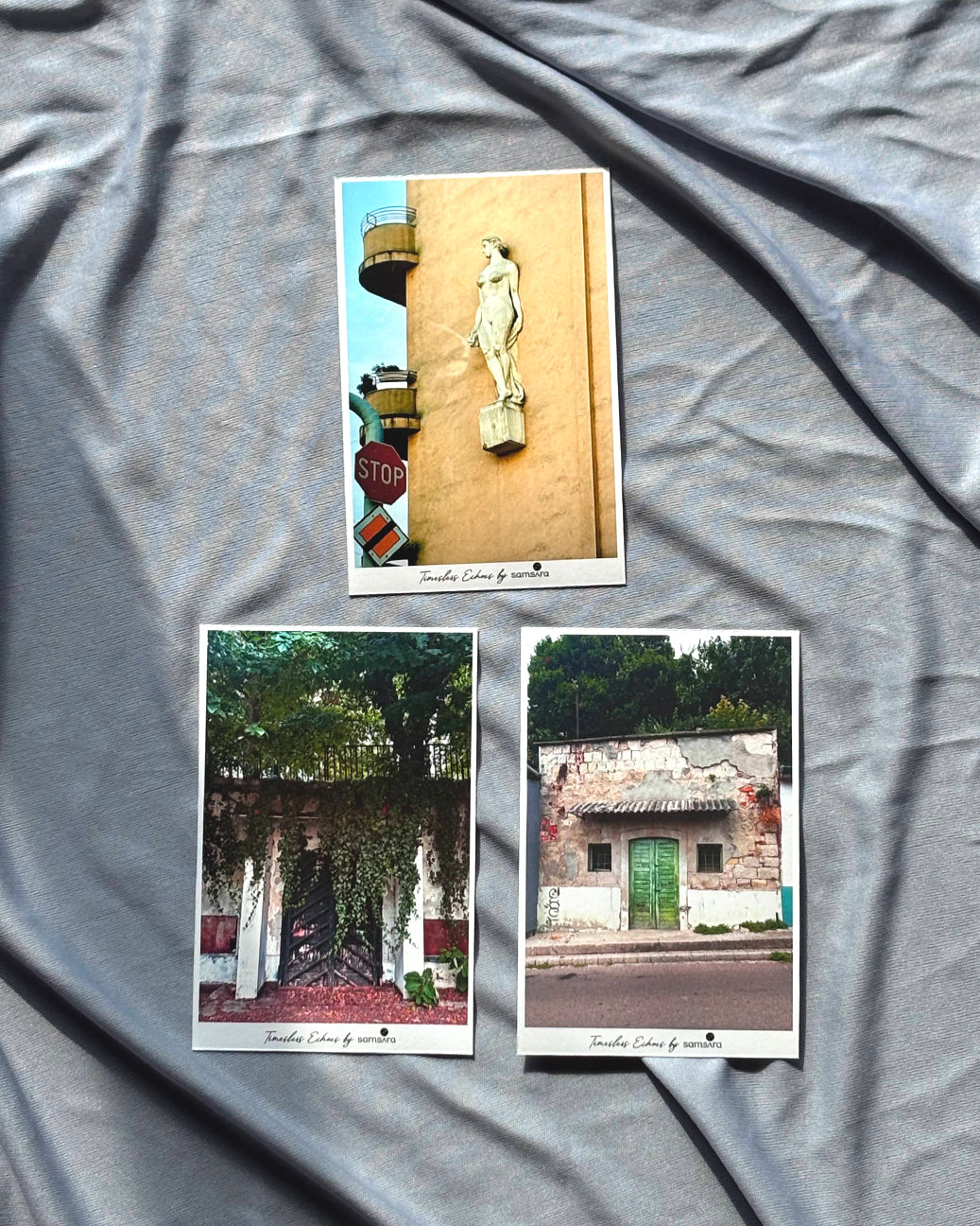 A set of three framed art prints laid out on a grey surface, featuring architectural details such as doorways and a statue.