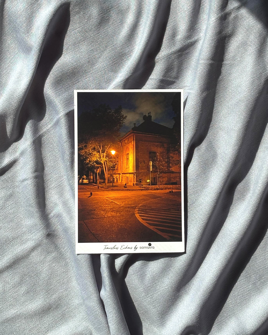 Postcard with a nighttime cityscape on a textured gray fabric background