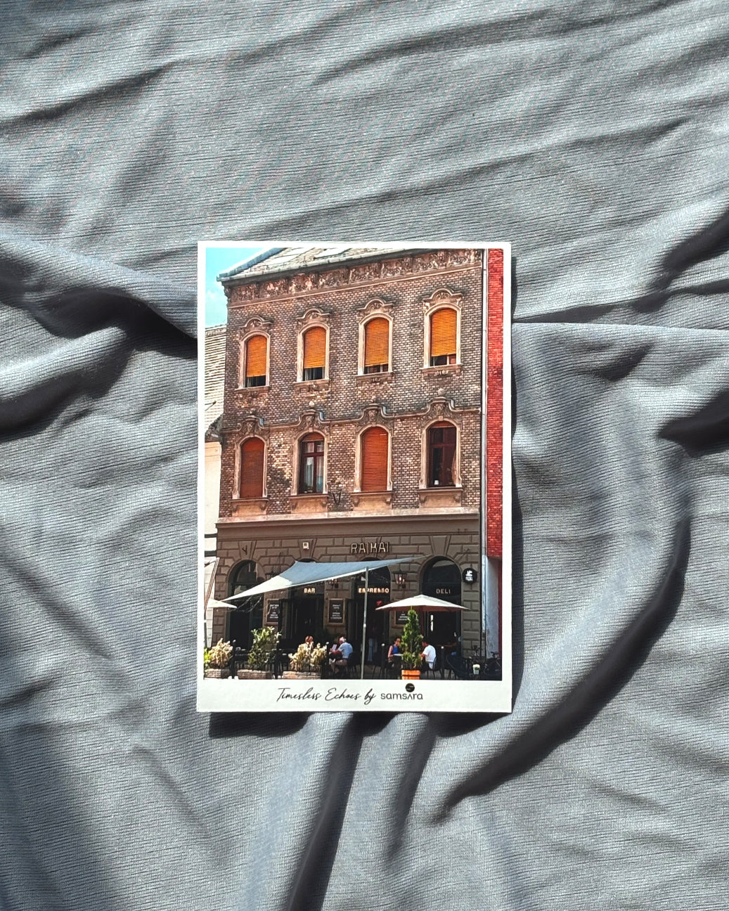 Postcard of a building with orange windows on a gray fabric background