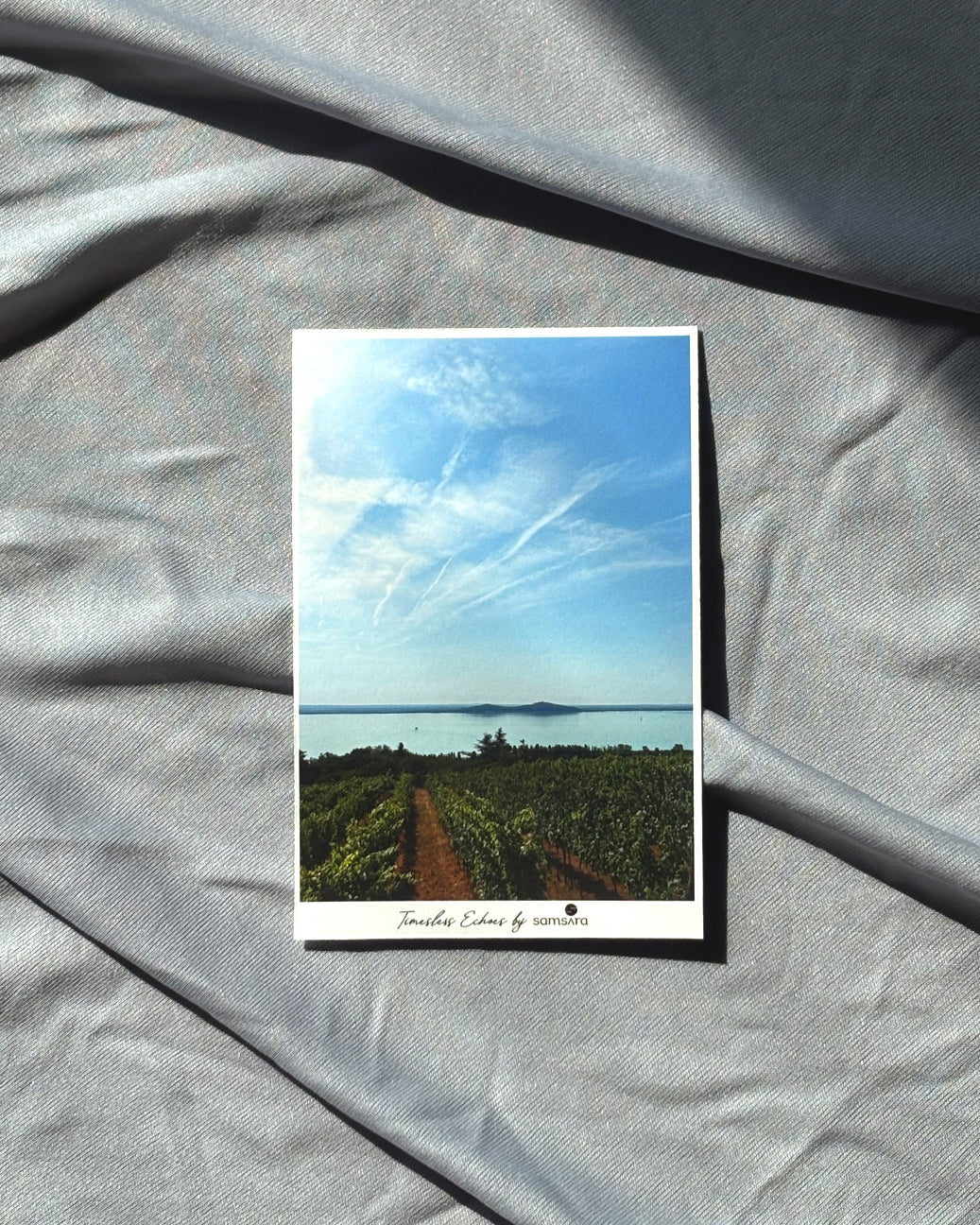 Greeting card with scenic view of a lake and vineyard on a textured gray surface