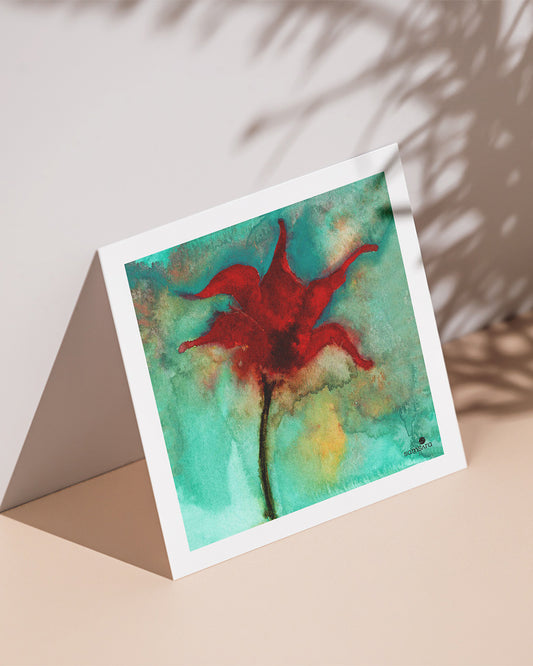 A mini art print of a red floral design on a turquoise background, displayed against a neutral backdrop with a shadow cast over it.