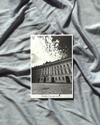 Black and white photo of a building on a textured gray fabric background