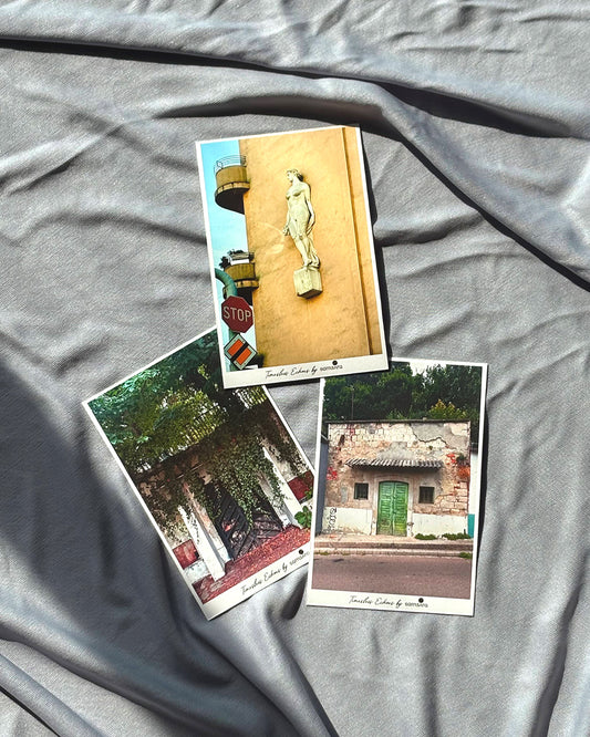 A set of three framed art prints laid out on a grey surface, featuring architectural details such as doorways and a statue.