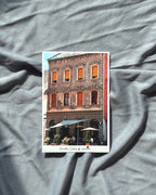 Postcard of a building with orange windows on a gray fabric background
